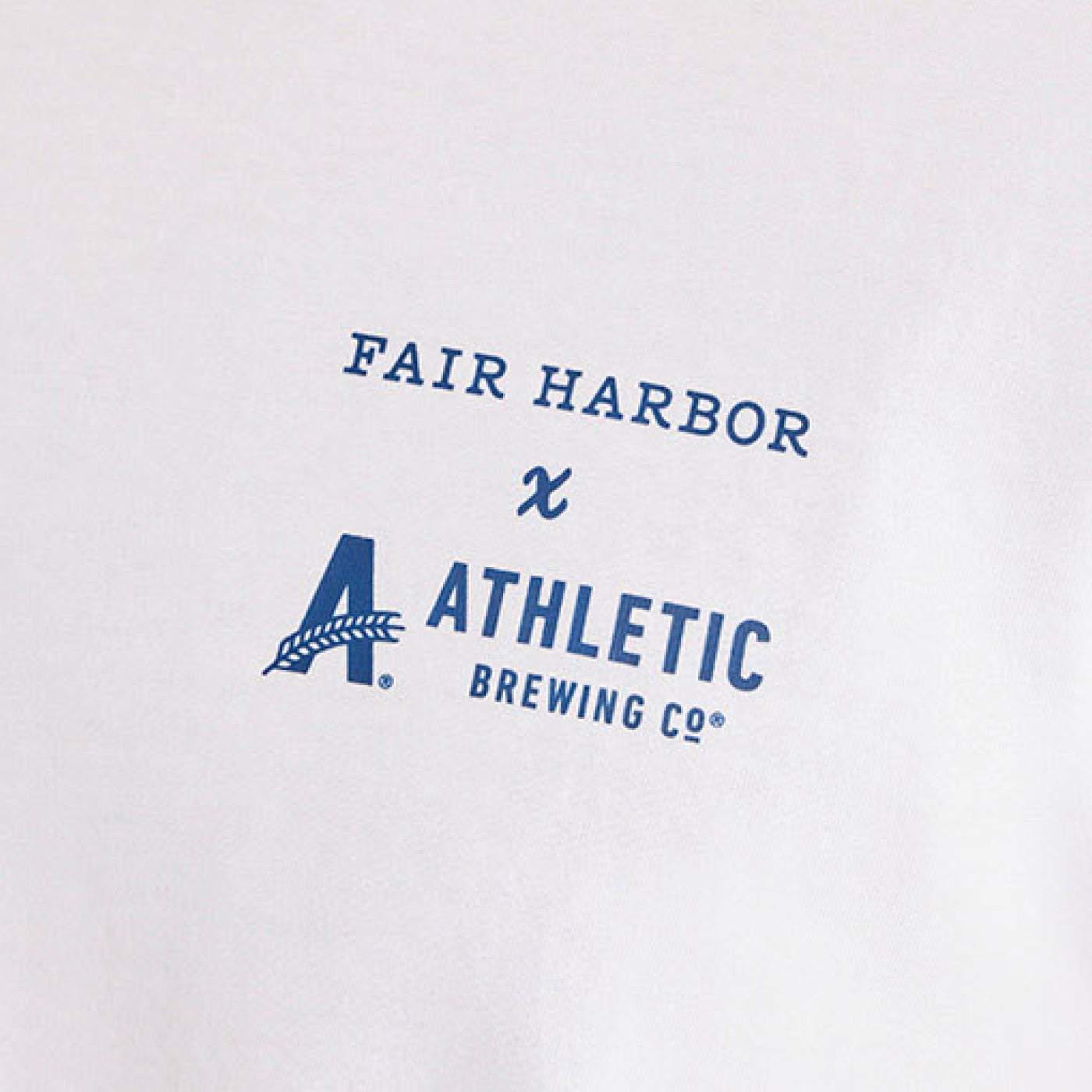 Close-up detail of a white T-shirt showing the blue ‘Fair Harbor x Athletic Brewing Co.’ logo printed on the chest.