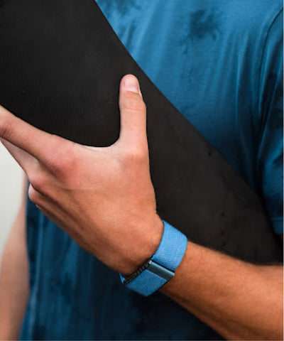Bluw Whoop band on wrist holding yoga mat