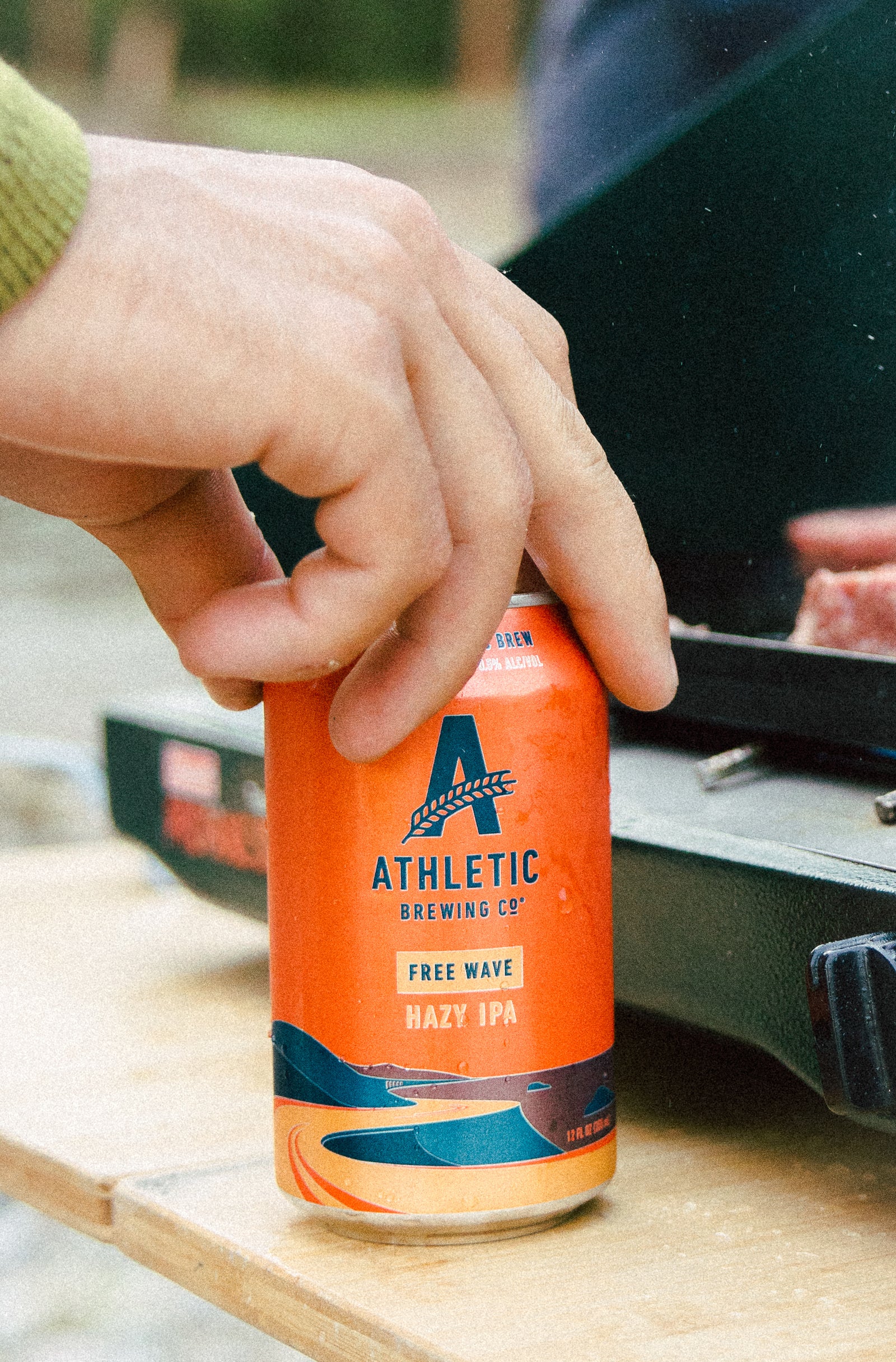 Hand touching a can of Free wave next to a grill