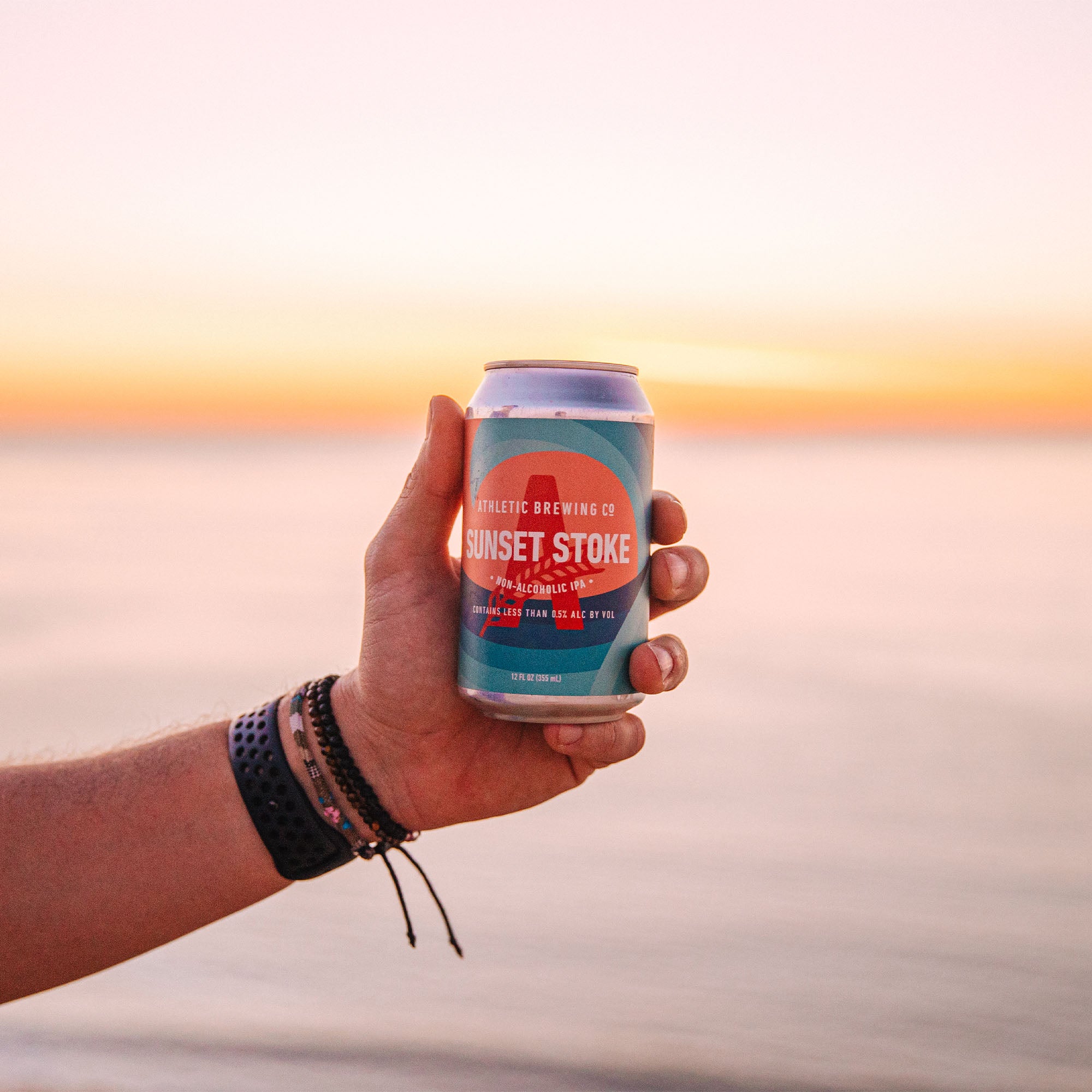 holding can of sunset stoke near ocean