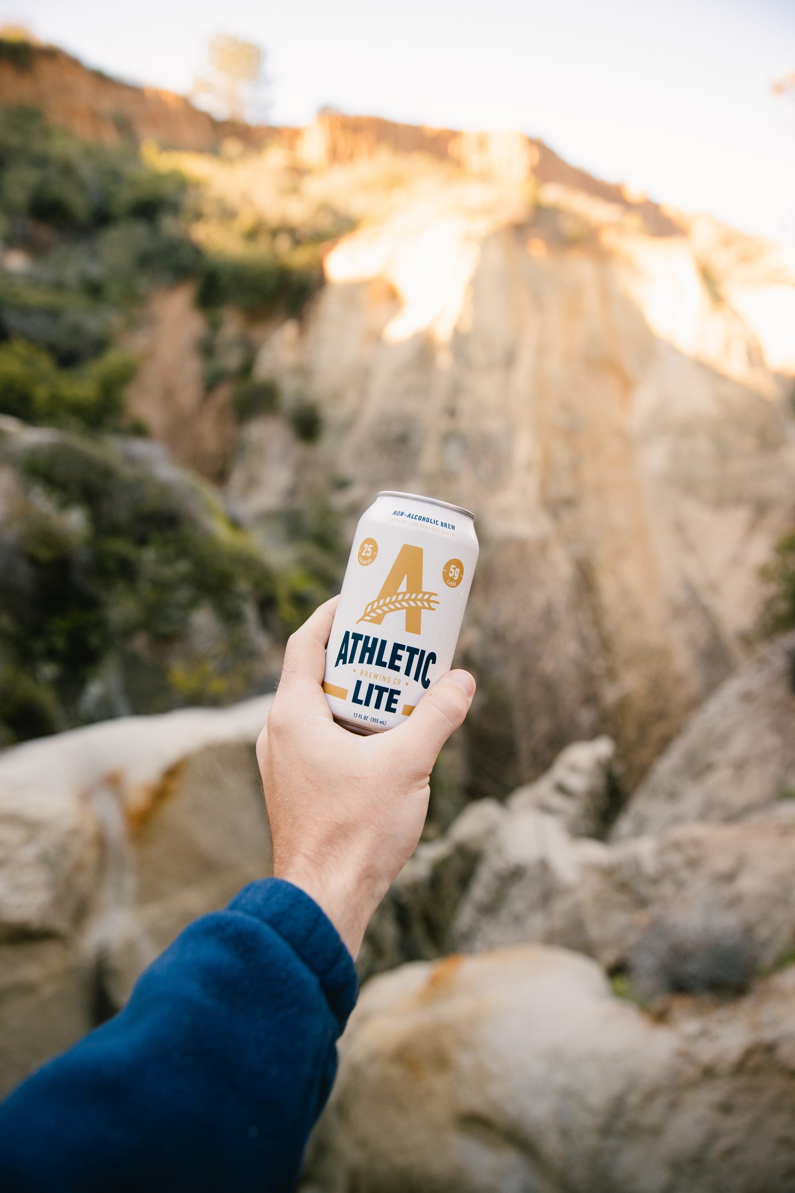 Lite can being held in hand in front of mountain