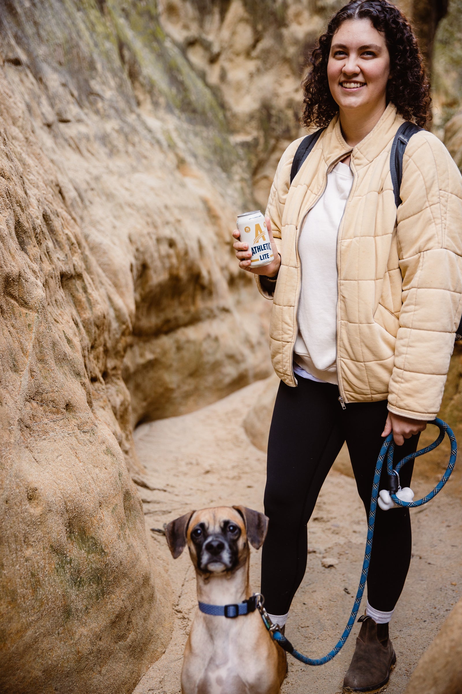 Lite can being held by woman and next to dog