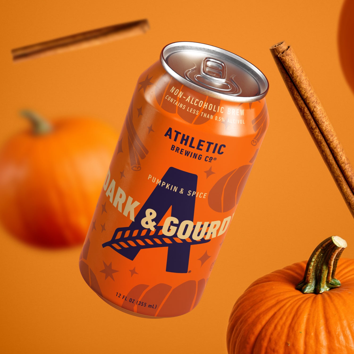 Athletic Brewing Dark & Gourdy Pumpkin & Spice non-alcoholic brew can with pumpkins and cinnamon sticks on an orange background.