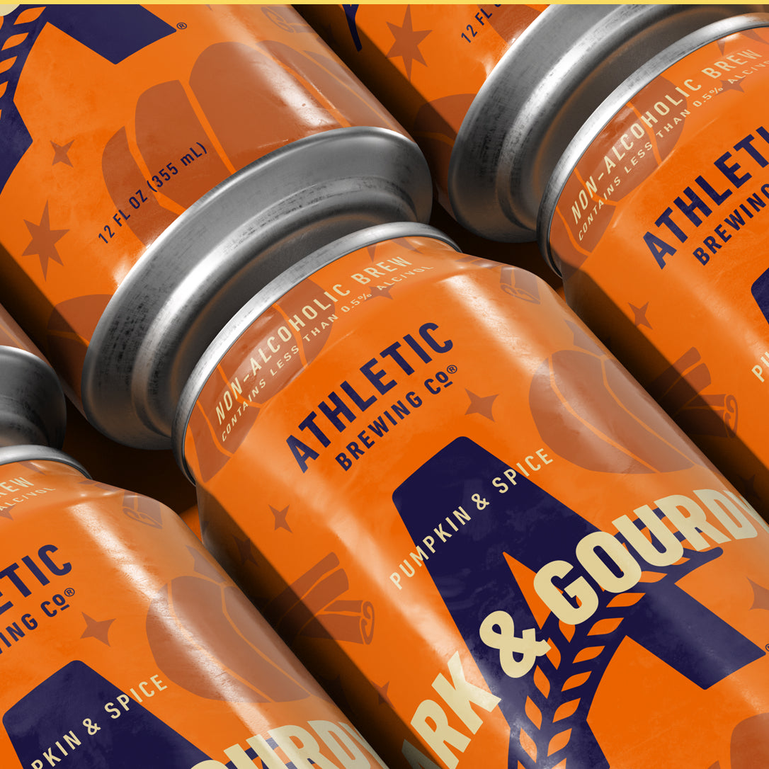 Close-up of multiple Athletic Brewing Dark & Gourdy Pumpkin & Spice non-alcoholic brew cans with bright orange labels and condensation.