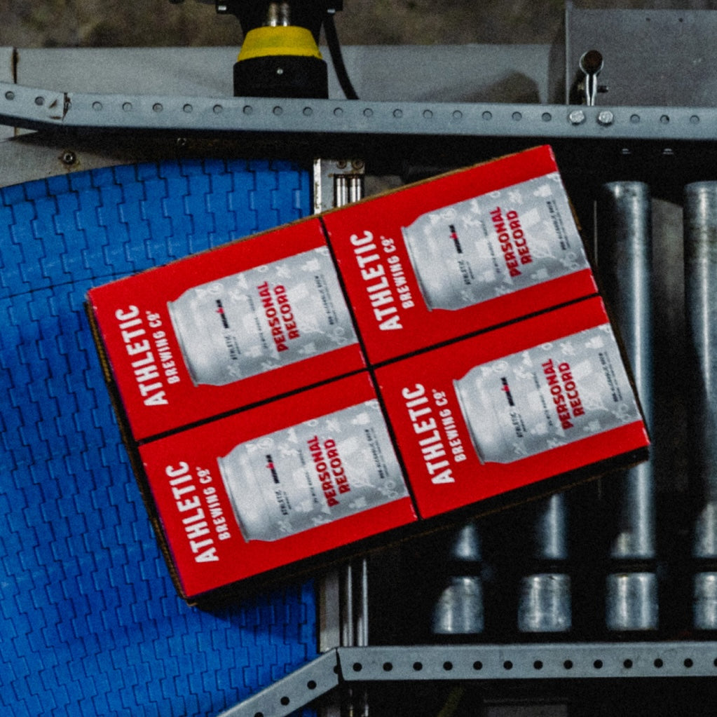 Four 6-packs of Personal Record IPA on a brewery conveyor.