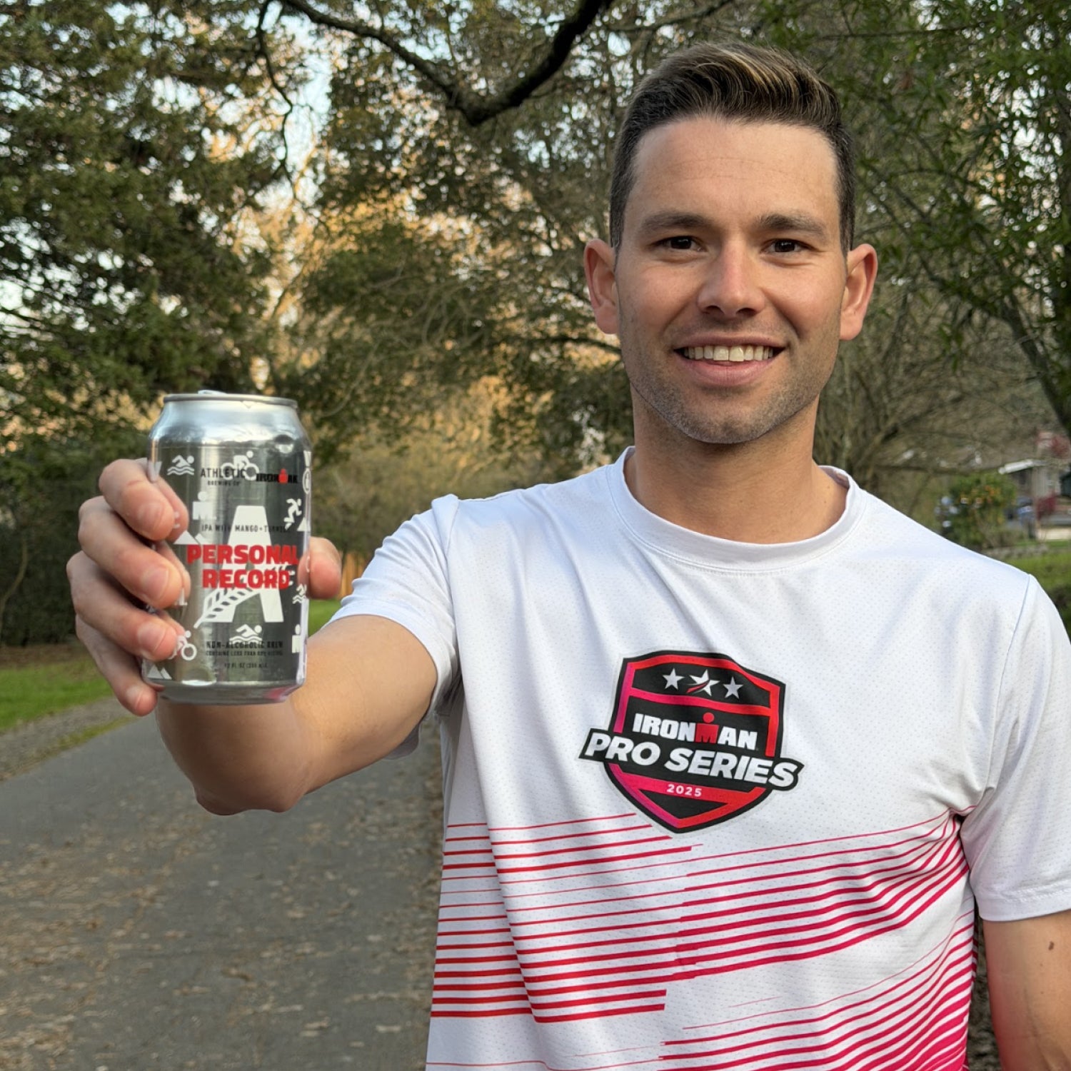 Professional triathlete Justin Riele holding out a Personal Record IPA.