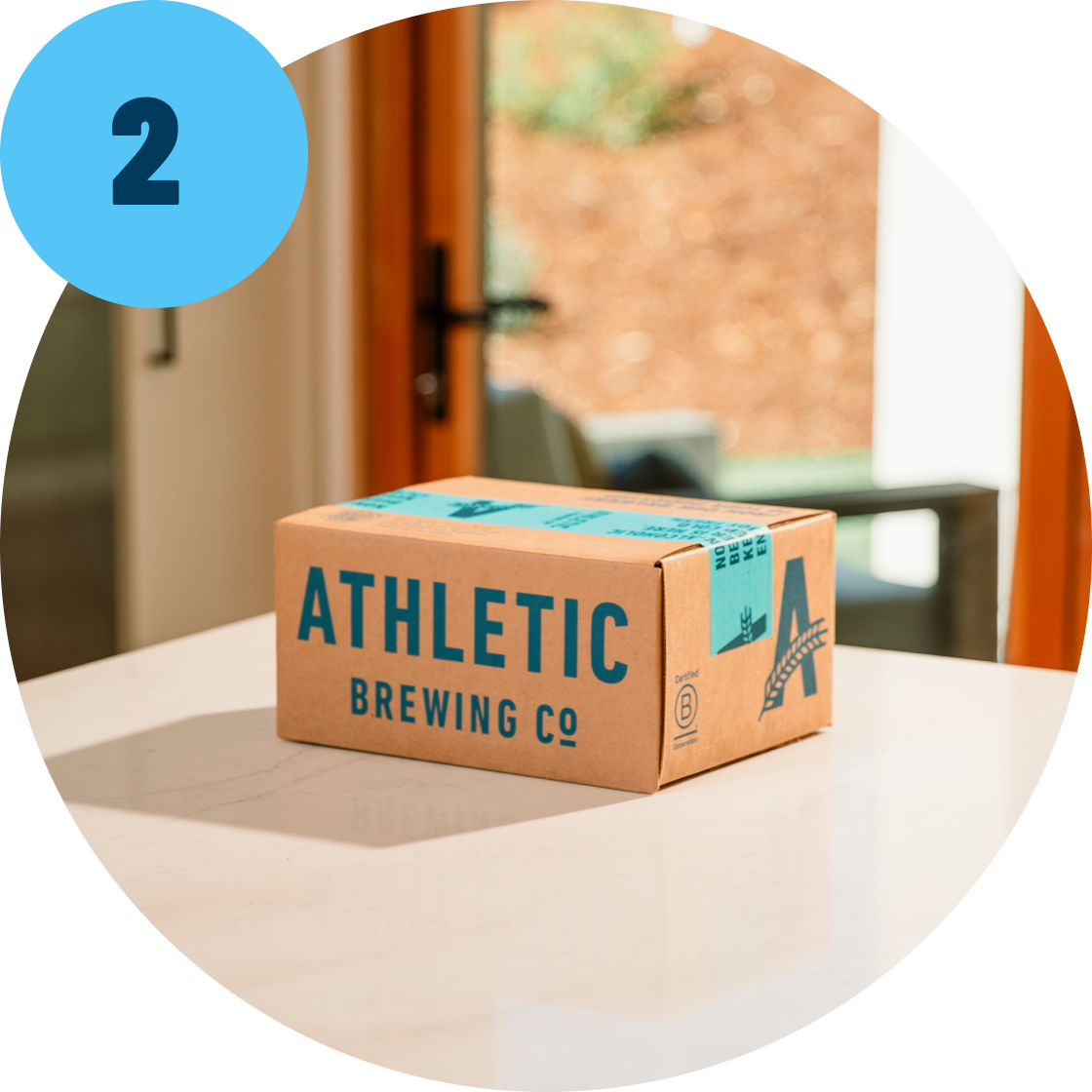 Step 2 Cardboard box with 'Athletic Brewing Co' branding on a table.