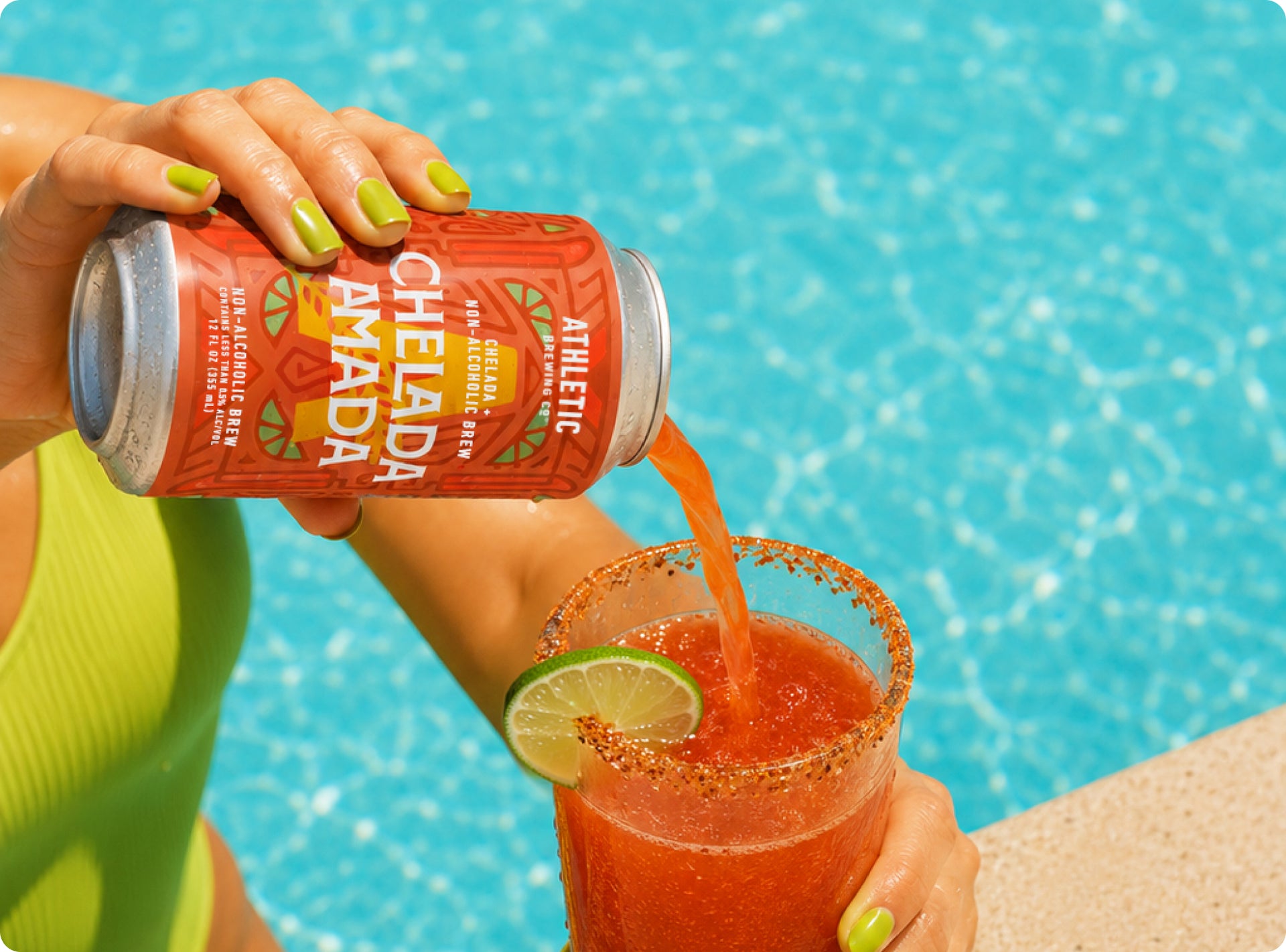 pouring chelada into a glass next to pool