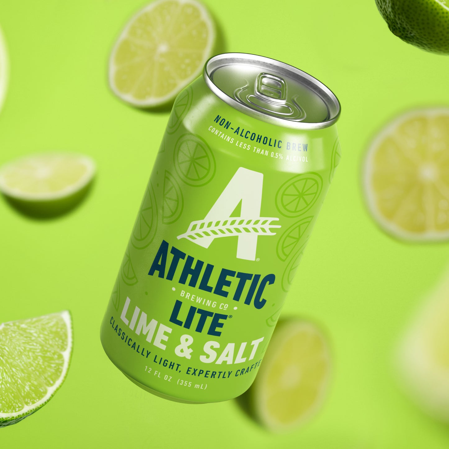 A can of Athletic Lite Lime & Salt non-alcoholic beer floating diagonally against a bright lime green background with scattered lime slices around it.