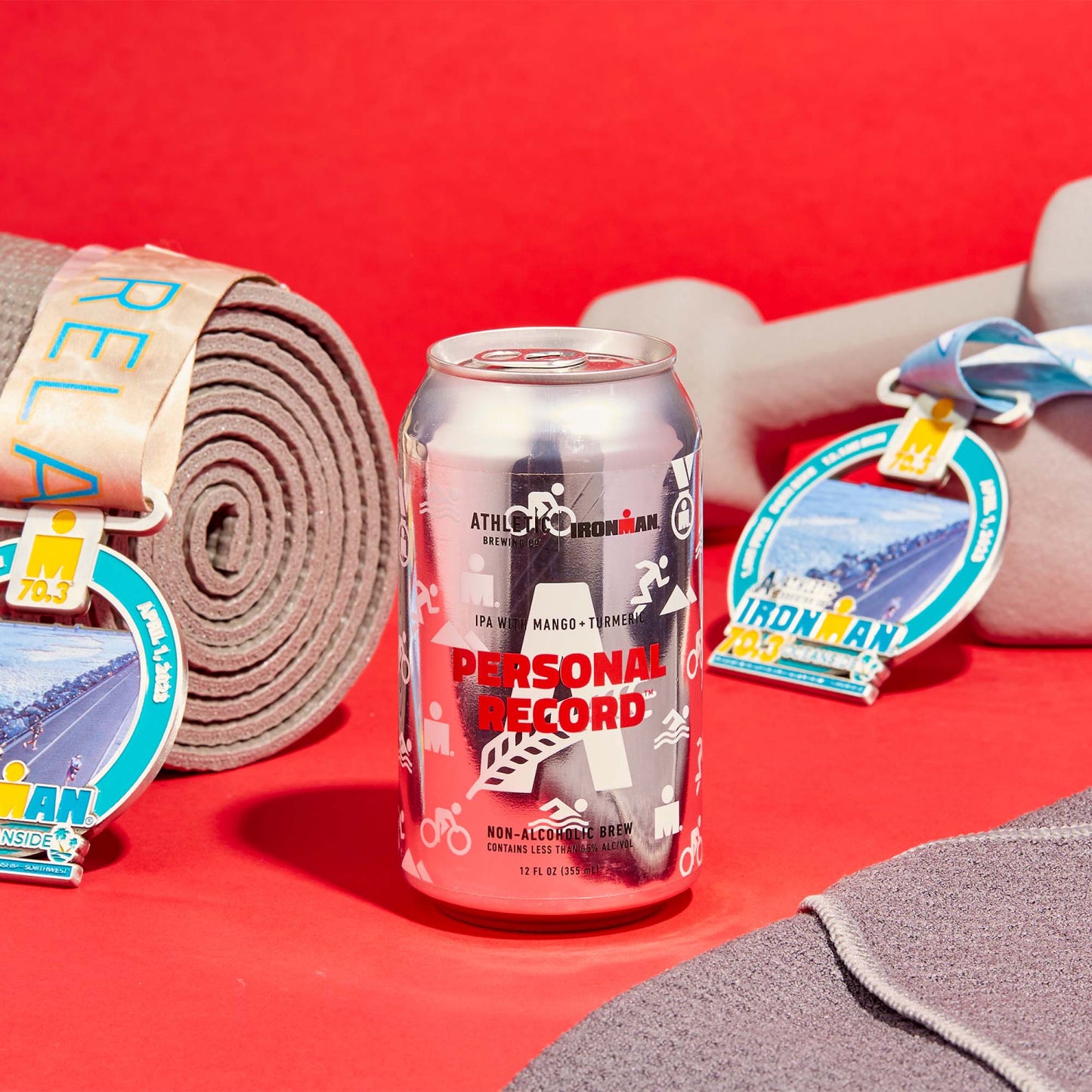 Personal Record IPA can with Ironman medals and workout gear.