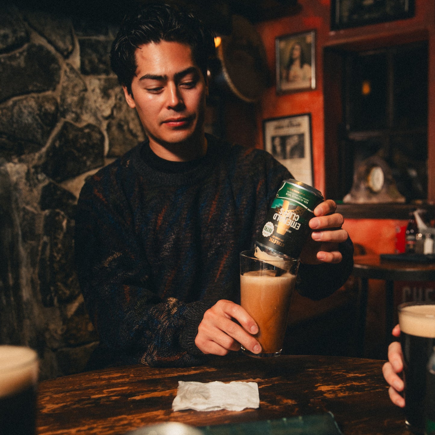 Person pouring a can of Nitro Emerald Cliffs into a glass.