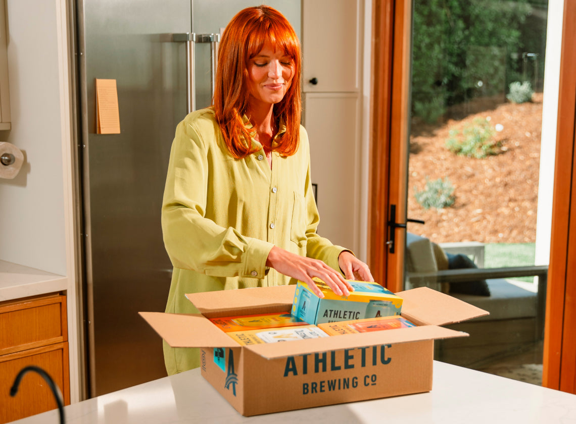 person opening a box of Athletic in a kitchen