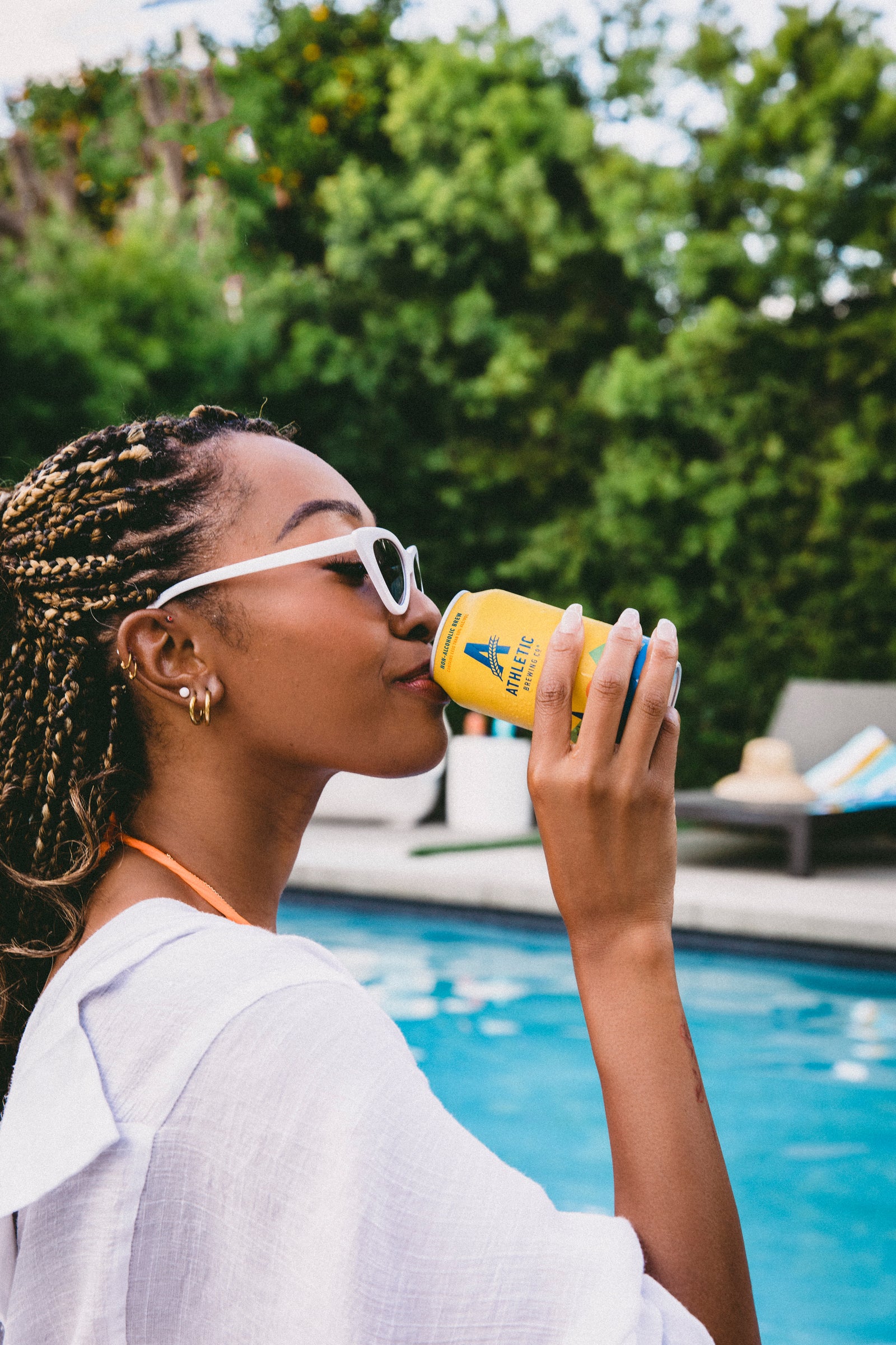 Woman drinking a can of Upside Dawn next to a pool